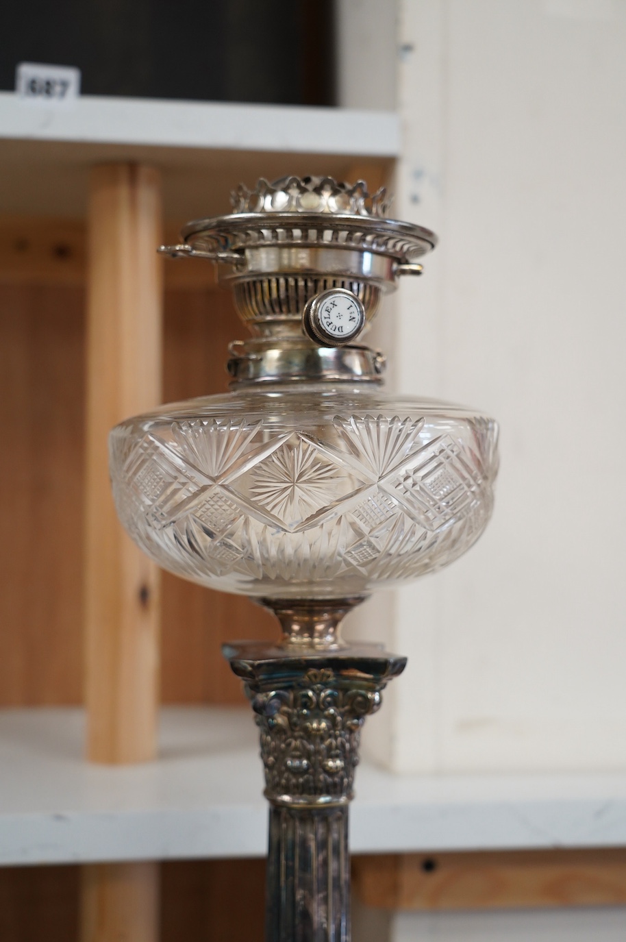 A silver plated oil lamp in the form of a Corinthian column with cut glass reservoir, 76cm high. Condition - fair to good, missing chimney and shade